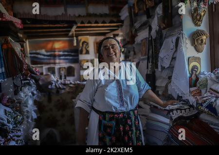 Karpathos, Griechenland. 10. August 2021. Frau Rigopoula in ihrem Laden mit lokalen handgewebten Textilien, traditionellen Schals und traditionellen Mini-Kostümen für Puppen, Olympos Dorf, Karpathos Insel. Karpathos ist die zweitgrößte Insel des griechischen dodekanischen Inselkomplexes in der südöstlichen Ägäis. Die Insel Karpathos hat immer noch ihre traditionelle Lebensweise, wie das Dorf Olympos, wo die Einheimischen noch immer die traditionellen Kostüme tragen. (Foto von Maria Makraki/SOPA Images/Sipa USA) Quelle: SIPA USA/Alamy Live News Stockfoto