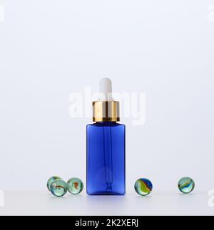 Blaue Glasflasche mit Pipette für Kosmetika, Öle und Serum. Werbung und Produktwerbung Stockfoto