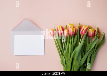 Grußkarten-Mockup oder Dankeskartenvorlage mit Tulpenstrauß auf beigem Hintergrund. Stockfoto