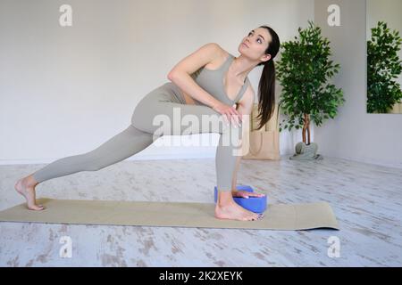 Junge schöne Frau praktiziert Yoga in einem hellen modernen Studio. Gesunder Lebensstil. Stockfoto