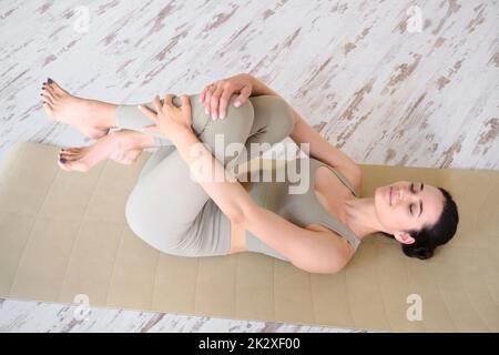Eine junge Frau mit einem athletischen Körper liegt mit geschlossenen Augen auf einer Yogamatte. Yoga üben. Stockfoto