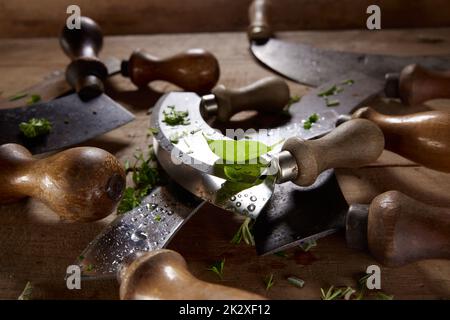 Ein Set altmodischer Mezzaluna-Messer mit gehacktem Grün Stockfoto