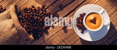 Schaumige Kaffeecrema in kleiner Tasse mit Untertasse auf Holz Stockfoto