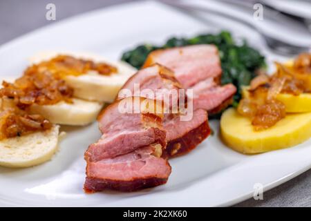 Geräucherte Flanke mit Kartoffel- und Brotknödeln und Spinat Stockfoto