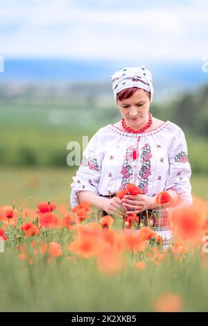 Frau in ukrainischer Nationaltracht auf einem blühenden Mohnfeld Stockfoto