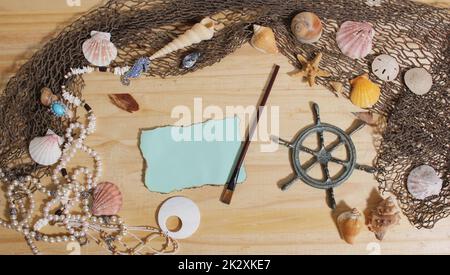 Leeres Papier mit verbrannten Kanten auf Holzhintergrund mit Meeresmuscheln und Fischernetz. Nautisches und Küstenthema Stockfoto