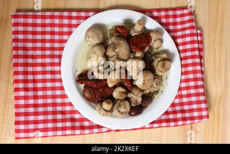 Pilze, sonnengetrocknete Tomaten, Oliven und Kapern in Olivenöl auf rustikalem Tisch Stockfoto