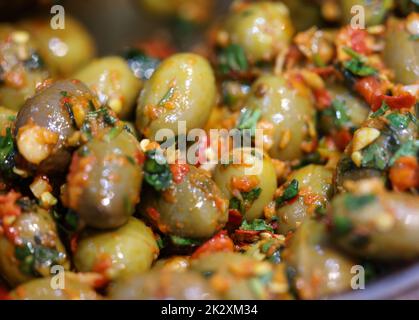 Grüne Oliven in Kräutermarinade in einer alten Holzschale Stockfoto