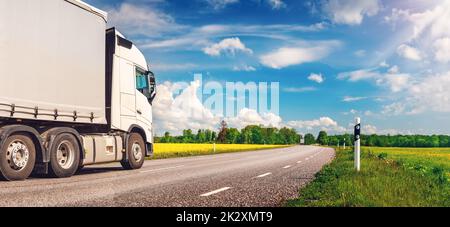 LKW bewegt sich an sonnigen Tagen im Frühjahr auf der asphaltierten Landstraße Stockfoto