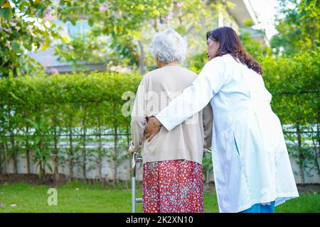 Arzt Hilfe Asian ältere Frau Behinderung Patient gehen mit Wanderer im Park, medizinisches Konzept. Stockfoto