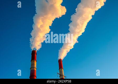 Weißer Rauch kommt aus den Rohren am blauen Himmel Stockfoto