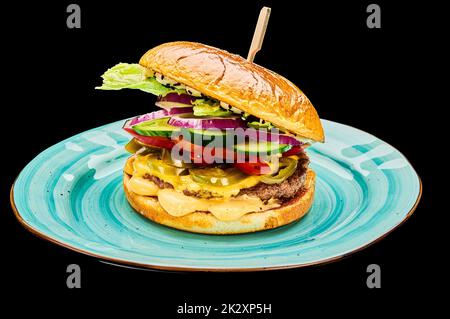 Saftiger bbq Burger mit Käse, Tomaten, roten Zwiebeln, Gurke liegt auf einem blauen Teller auf einem schwarzen isolierten Hintergrund Stockfoto