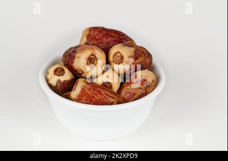 Schüssel mit Sagai-Datteln auf Weiß Stockfoto