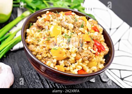 Gerstenporridge mit Hackfleisch in der Schüssel auf schwarzem Brett Stockfoto