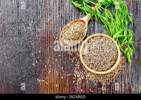 Kreuzkümmelsamen in Schüssel und Löffel mit Kräutern an Bord Stockfoto