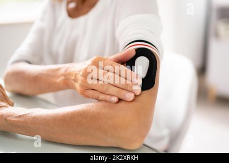 Frau zur Blutzuckerbestimmung mit einem kontinuierlichen Blutzuckermessgerät Stockfoto