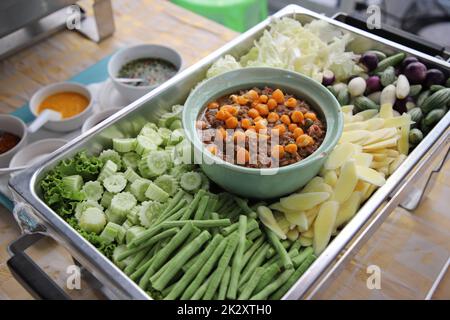 Thailändisches Essen, Nam Prik Kai Poo (Crabâ€™s Roe Chilli Dip) mit vielen Gemüsesorten in der Büffetschlange. Der Behälter ist eine rechteckige Edelstahlschale. Selektiver Fokus. Stockfoto