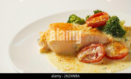Cremige Knoblauchbutter, Toskanischer Lachs. Lachsfilet mit Sahnesauce, Kirschtomaten und Brokkoli Stockfoto