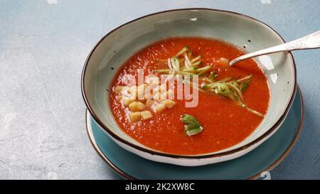 Schüssel mit hausgemachter Gazpacho Tomatensuppe, Croutons und Gurkenscheiben. Spanische Suppe auf Basis kalter Tomaten Stockfoto