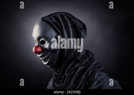 Scary Clown zeigt seine Zähne über dunklen nebligen Hintergrund Stockfoto