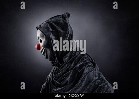 Scary Clown zeigt seine Zähne über dunklen nebligen Hintergrund Stockfoto