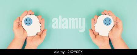 Einen Kopf mit einem traurigen und glücklichen Gesicht in den Händen halten, psychische Gesundheit, positive und negative Einstellung, Depression, Unterstützung und Bewertungssymbol, Emotionen Stockfoto