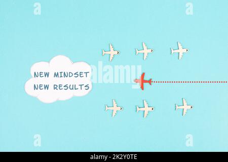 Red Airplane fliegt in die Cloud mit den Worten New Mindset New Results, Changing Lifestyle, Coaching und Improvement Concept, positive Thinking Stockfoto