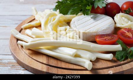 Camembert mit Streichkäse oder Käsepeitsche - salziger Snack-Käse mit Kirschtomaten und Kräutern auf Schneidebrett. Stockfoto