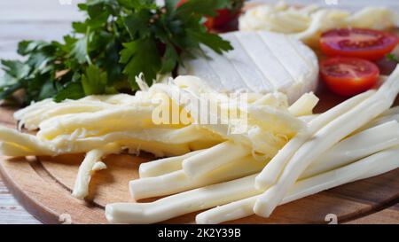 Camembert mit Streichkäse oder Käsepeitsche - salziger Snack-Käse mit Kirschtomaten und Kräutern auf Schneidebrett. Stockfoto