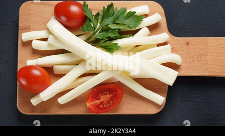 Streichkäse oder Käsepeitsche - salziger Snack-Käse mit Kirschtomaten und Kräutern auf Schneidebrett. Türkischer Käse Stockfoto