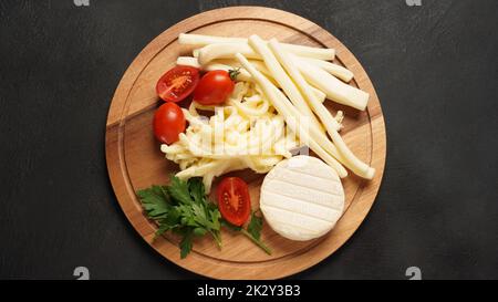 Camembert mit Streichkäse oder Käsepeitsche - salziger Snack-Käse mit Kirschtomaten und Kräutern auf Schneidebrett. Stockfoto