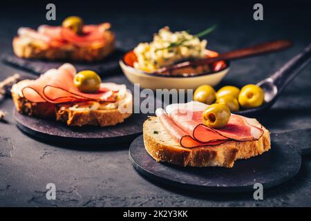 Gebratenes Brot mit Knoblauchbutter und seranaschinken und Oliven Stockfoto