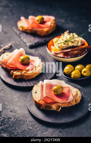 Gebratenes Brot mit Knoblauchbutter und seranaschinken und Oliven Stockfoto