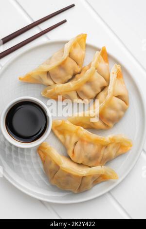 Chinesische Knödel und Sojasoße auf dem Teller. Stockfoto