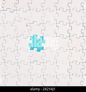Weißes Puzzle auf blauem Hintergrund, fehlende Teile, Zusammenarbeit im Team, Suche nach Lösungen, das letzte Stück Stockfoto