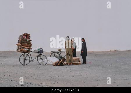 Gruppe von armen arbeitslosen Wandermännern, die recycelbaren Kartonabfall auf den Straßen sammeln, um zu überleben.Obdachlose. Stockfoto