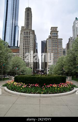 CHICAGO, ILLINOIS, USA - 12. Mai 2018: Blick vom Millennium Park in die städtischen Schluchten der Innenstadt von Chicago mit dem Zug im Hintergrund Stockfoto