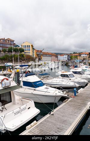 Wunderschöner Yachthafen von Llanes City, im Norden Spaniens - Asturien. Blick auf die angedockten Boote. Im Hintergrund die Stadt Llanes mit bunten Gebäuden und Schönheit Stockfoto