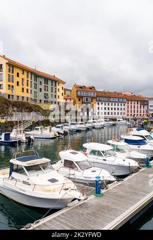 Wunderschöner Yachthafen von Llanes City, im Norden Spaniens - Asturien. Blick auf die angedockten Boote. Im Hintergrund die Stadt Llanes mit bunten Gebäuden und Schönheit Stockfoto