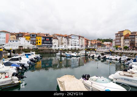 Wunderschöner Yachthafen von Llanes City, im Norden Spaniens - Asturien. Blick auf die angedockten Boote. Im Hintergrund die Stadt Llanes mit bunten Gebäuden und Schönheit Stockfoto