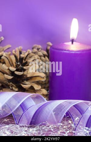 Weihnachtsszene mit brennender Kerze und Geschenkband in lila Ton Stockfoto