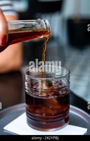 Gießen kalt Gebräu Eiskaffee in Glas Tasse mit Eiswürfeln, Kaffee consept Stockfoto