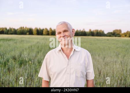 Lächelnder älterer Landwirt, der auf dem Bauernhof steht Stockfoto