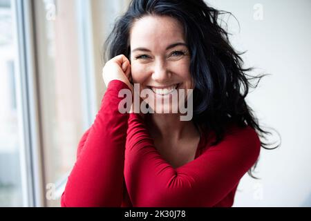 Fröhliche Brünette Frau am Fenster Stockfoto