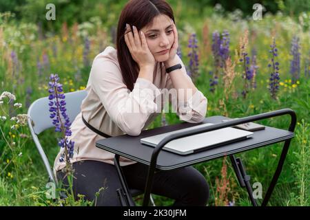 Müde Freiberufler an der Rezeption sitzen in Lupinenblumen Wiese Stockfoto