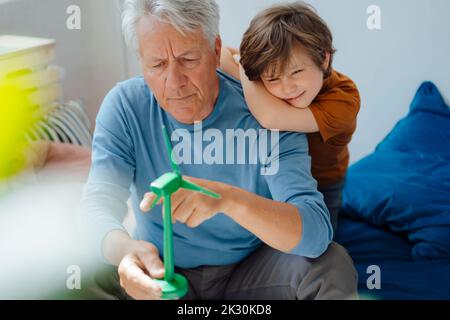 Großvater und Enkel analysieren zu Hause das Windenergieanlagenmodell Stockfoto