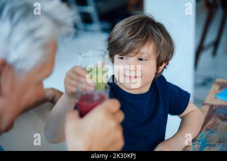 Enkel toasten Saft mit Großvater zu Hause Stockfoto