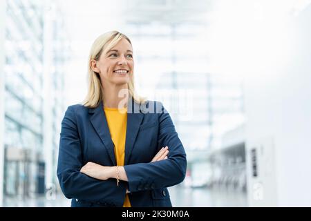 Kontemplative Geschäftsfrau mit gekreuzten Armen Stockfoto