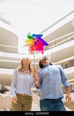 Spielerische Geschäftskollegen blasen mehrfarbige Windrad Spielzeug Stockfoto