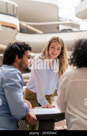 Lächelnde Geschäftsfrau im Gespräch mit Kollegen Stockfoto